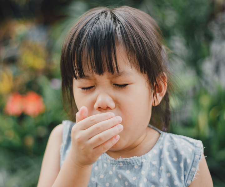 An elementary-aged girl sneezing